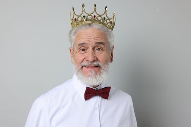 Photo of Senior man wearing luxury crown on grey background