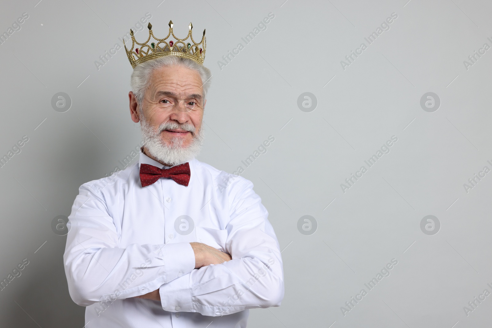 Photo of Senior man wearing luxury crown on grey background, space for text