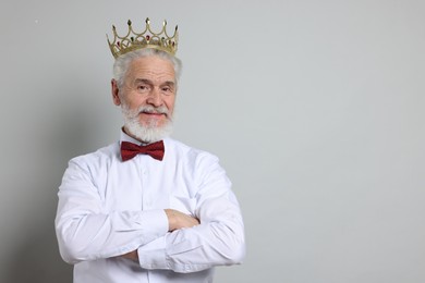 Photo of Senior man wearing luxury crown on grey background, space for text