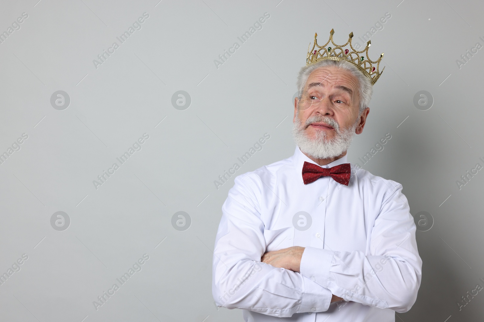 Photo of Senior man wearing luxury crown on grey background, space for text