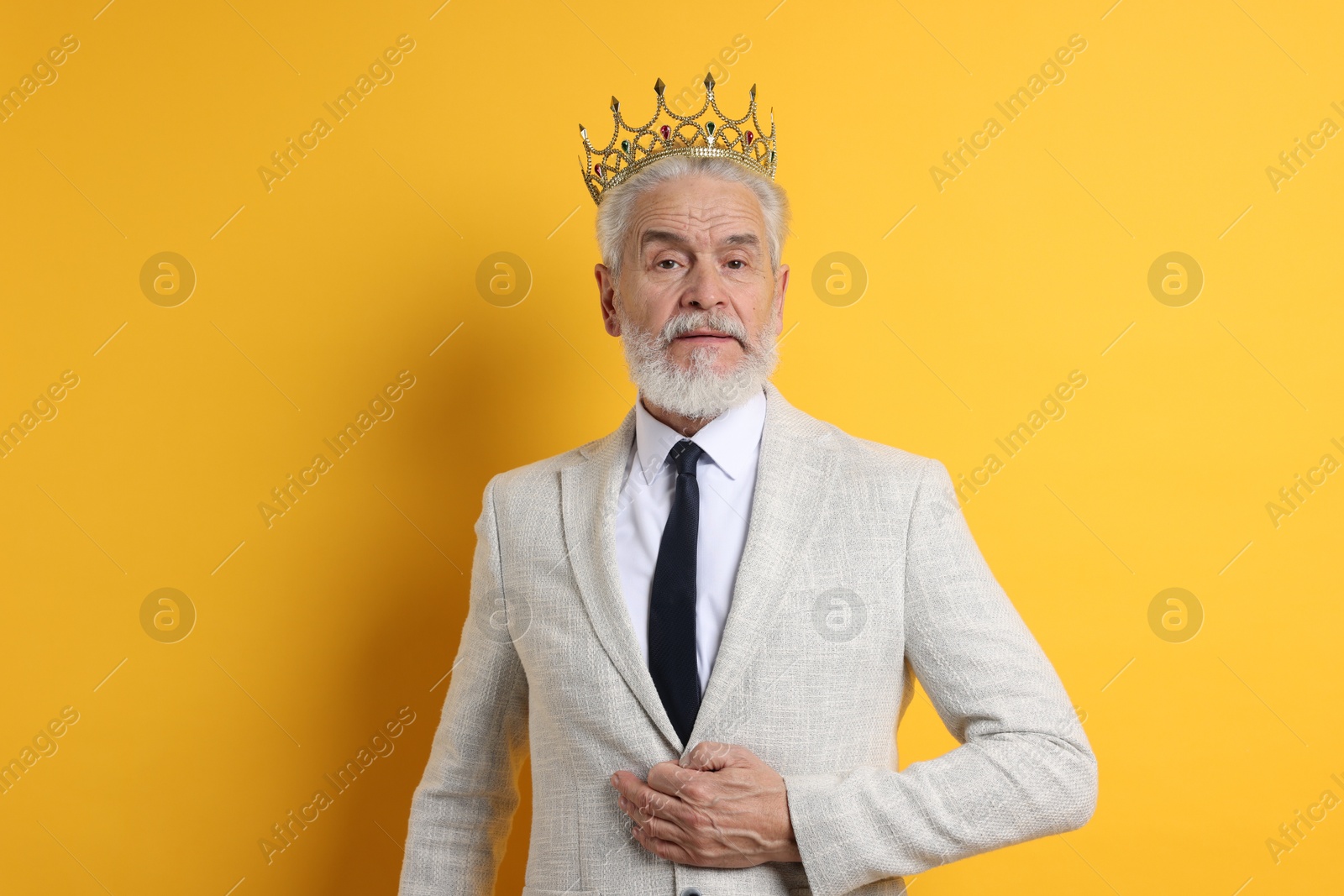 Photo of Senior man wearing luxury crown on orange background