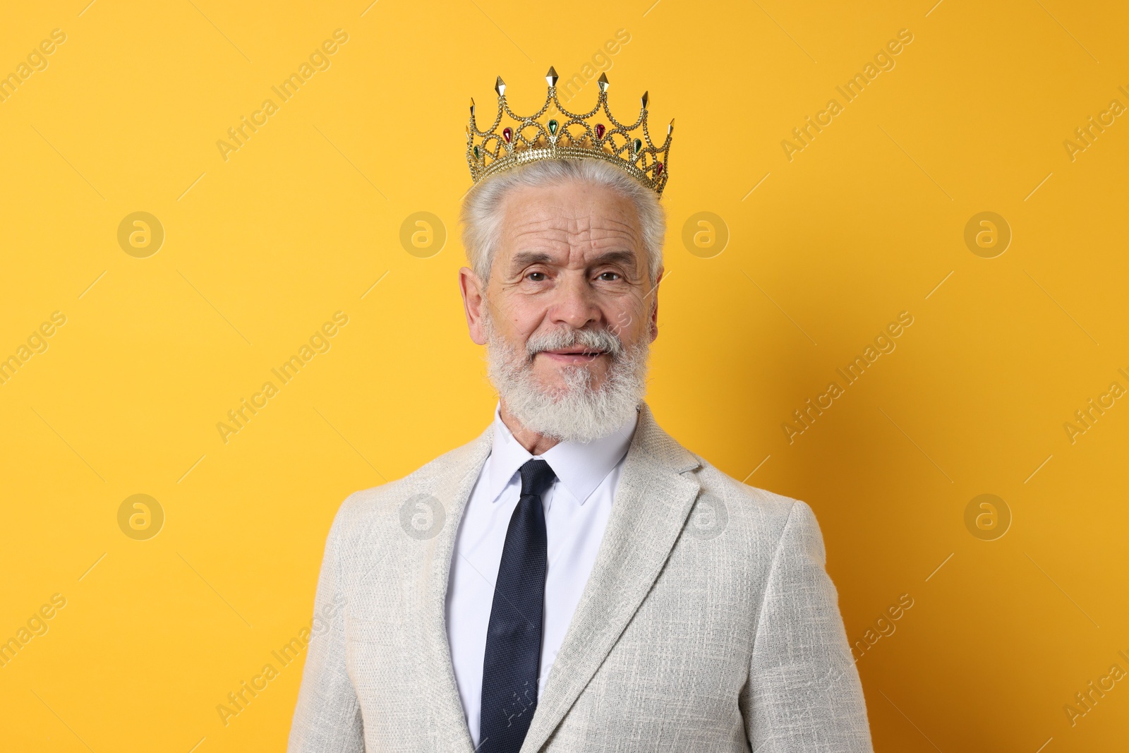 Photo of Senior man wearing luxury crown on orange background