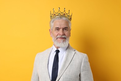 Photo of Senior man wearing luxury crown on orange background