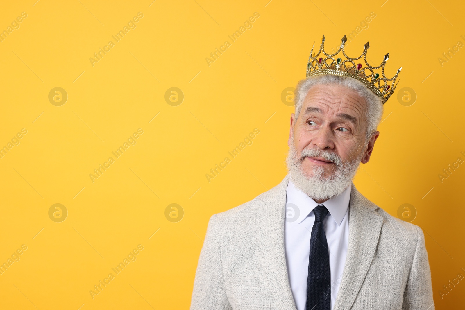 Photo of Senior man wearing luxury crown on orange background, space for text