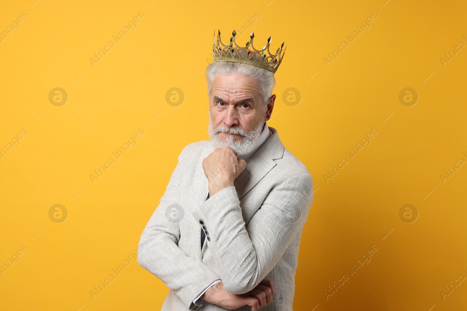 Photo of Senior man wearing luxury crown on orange background