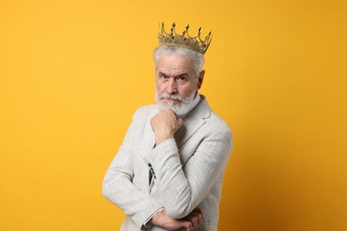 Photo of Senior man wearing luxury crown on orange background