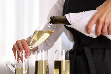 Photo of Waiter pouring champagne into glass indoors, closeup