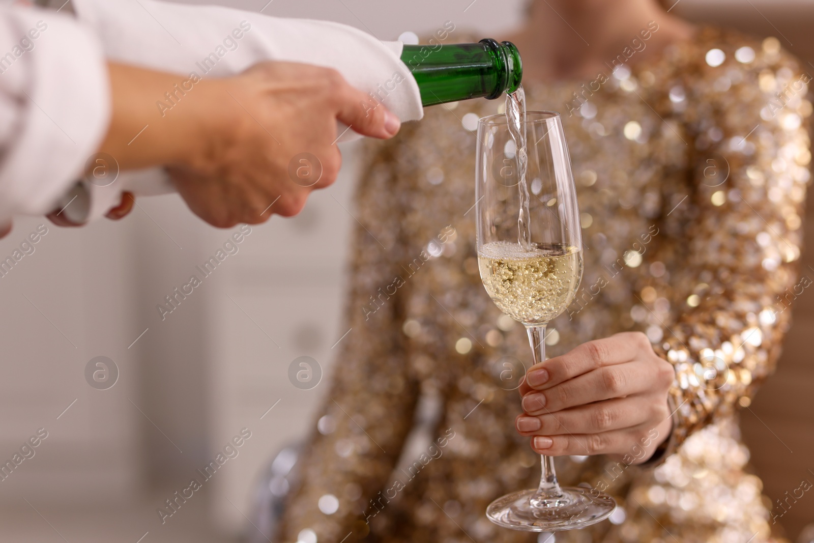 Photo of Waiter pouring champagne into woman's glass, closeup