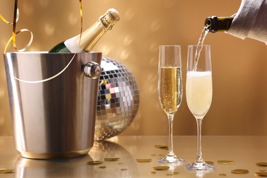 Photo of Pouring champagne into glass against golden background, closeup