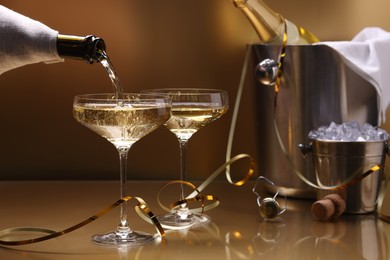 Photo of Pouring champagne into glass against golden background, closeup