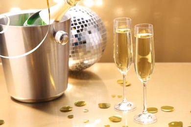 Photo of Champagne in glasses and ice bucket with bottle on golden background