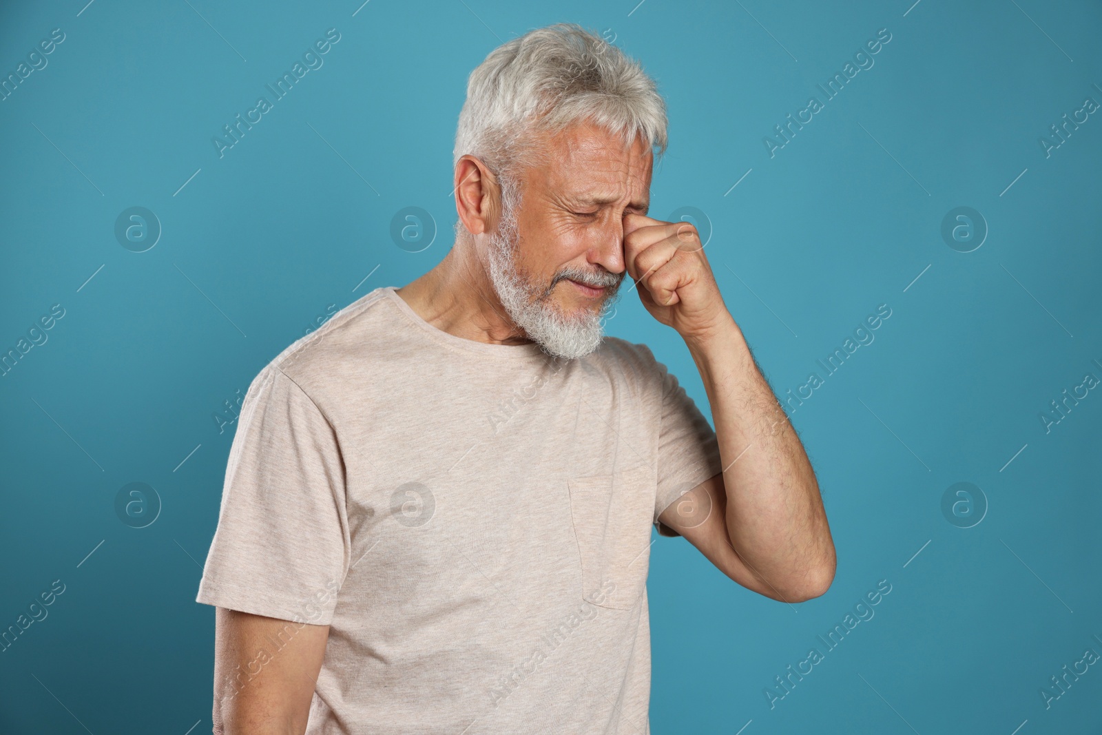 Photo of Sad senior man crying on light blue background