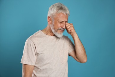 Photo of Sad senior man crying on light blue background