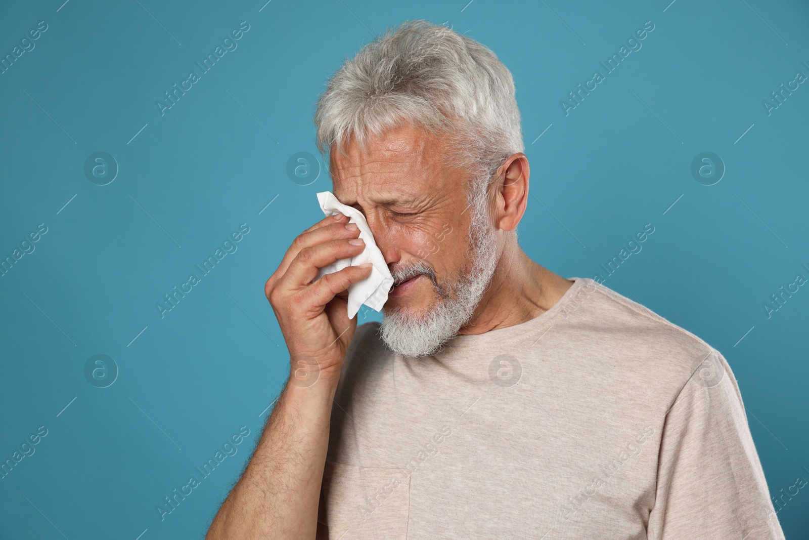 Photo of Sad senior man crying on light blue background