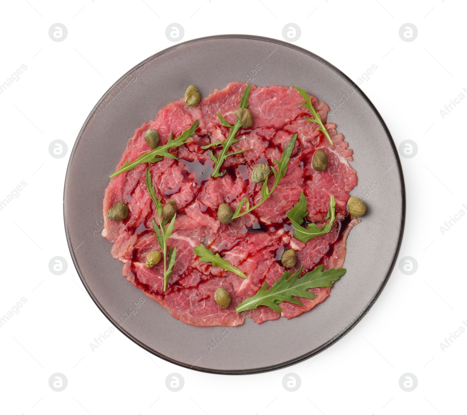 Photo of Fresh beef carpaccio with arugula, capers and sauce isolated on white, top view