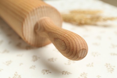 Photo of Wooden rolling pin on tablecloth, closeup view