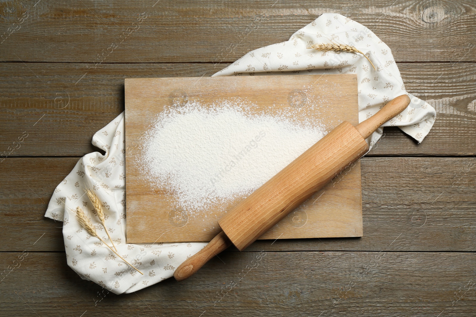 Photo of Rolling pin, board, flour and spikes on wooden table, top view