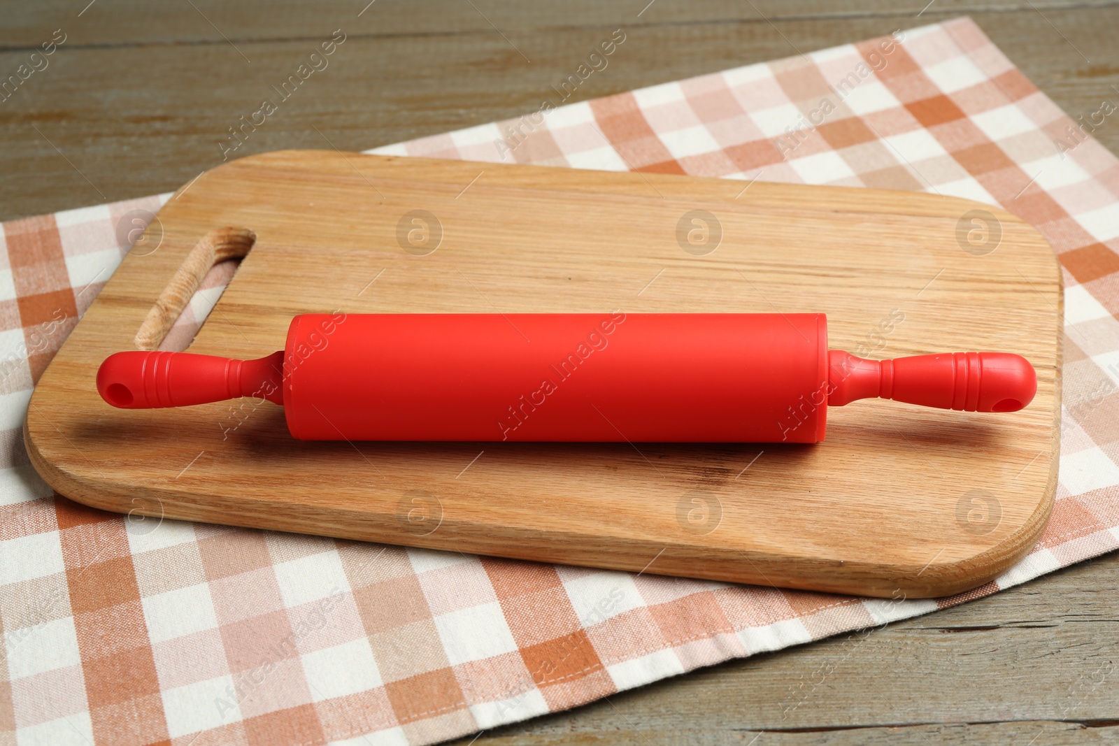 Photo of Red rolling pin and board on wooden table, closeup