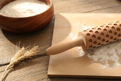 Photo of Rolling pin, flour and spikes on wooden table, closeup