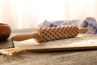 Photo of Rolling pin, flour, board, spikes and napkin on wooden table indoors, closeup