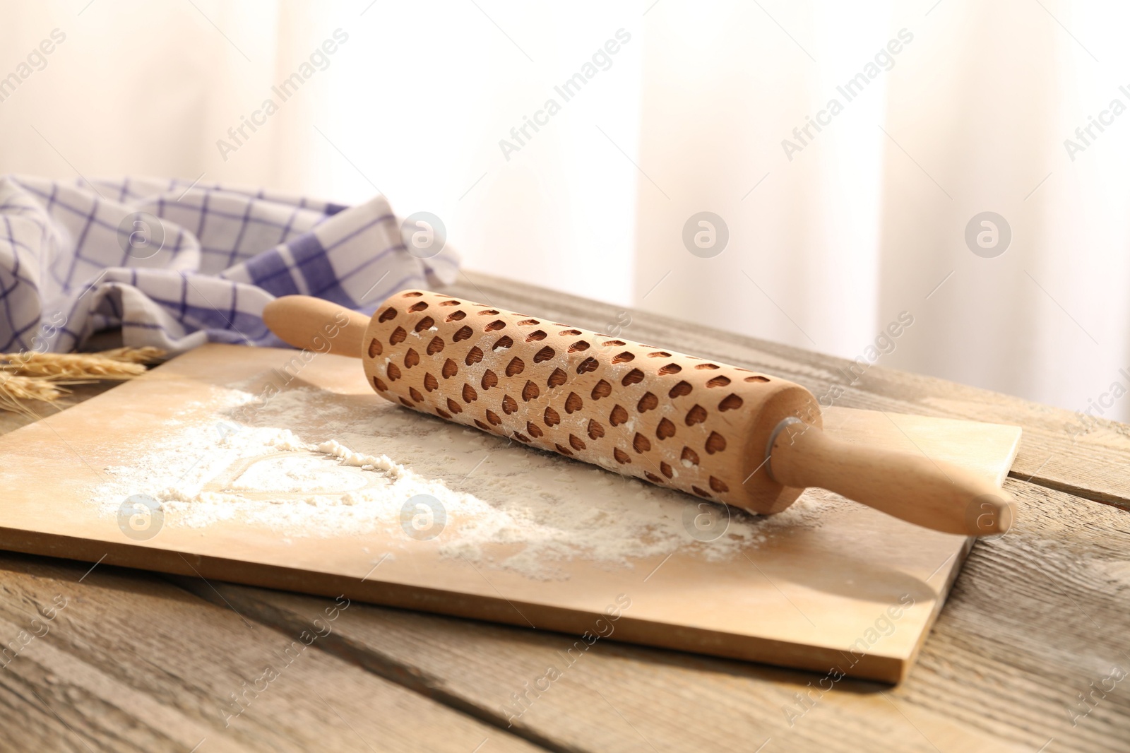 Photo of Rolling pin, flour, spikes and napkin on wooden table indoors, closeup