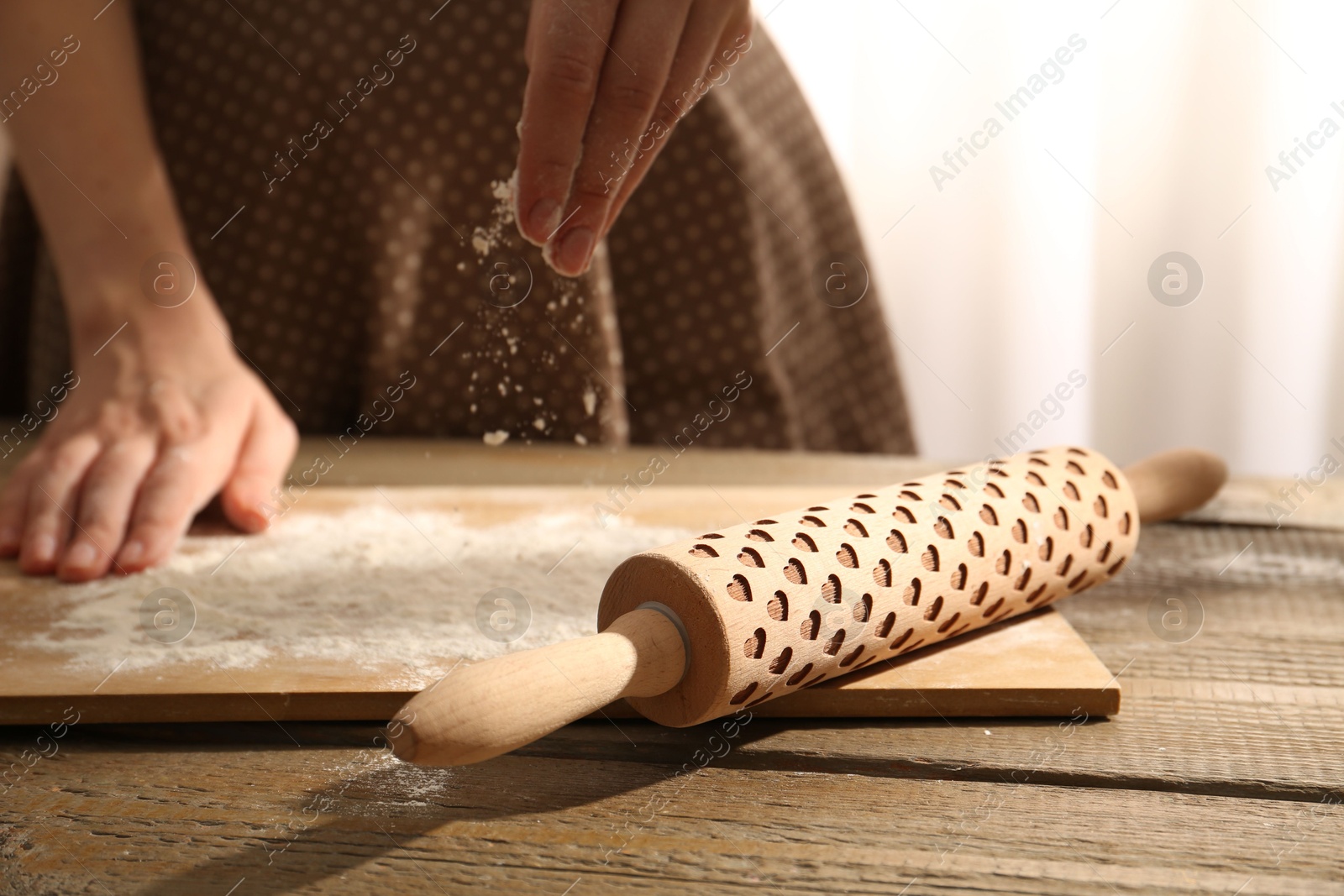 Photo of Woman with flour and rolling pin at wooden table indoors, closeup