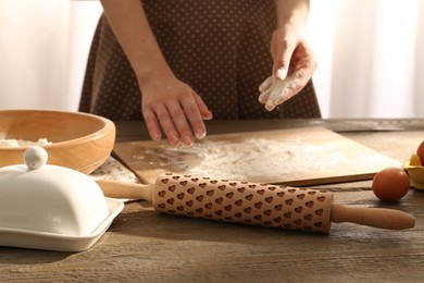 Photo of Woman with flour and rolling pin at wooden table indoors, closeup