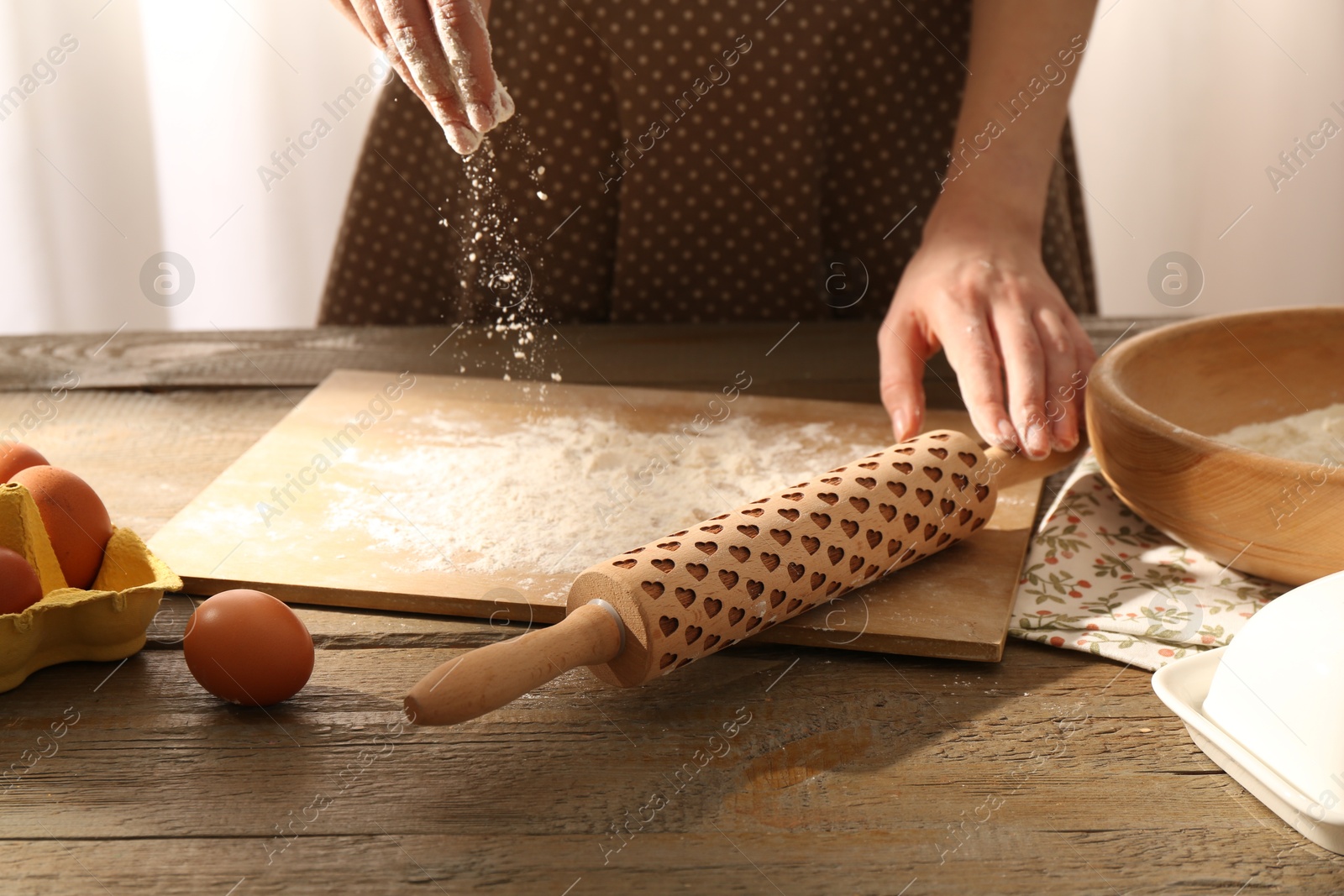 Photo of Woman with flour and rolling pin at wooden table indoors, closeup