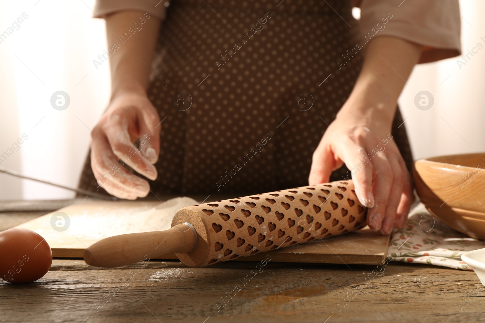 Photo of Woman with rolling pin at wooden table indoors, closeup