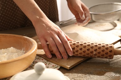 Photo of Woman with rolling pin at wooden table indoors, closeup