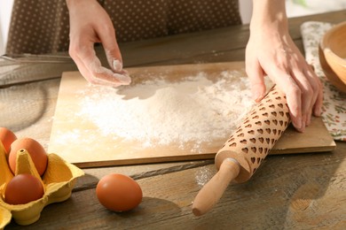 Photo of Woman with rolling pin at wooden table indoors, closeup