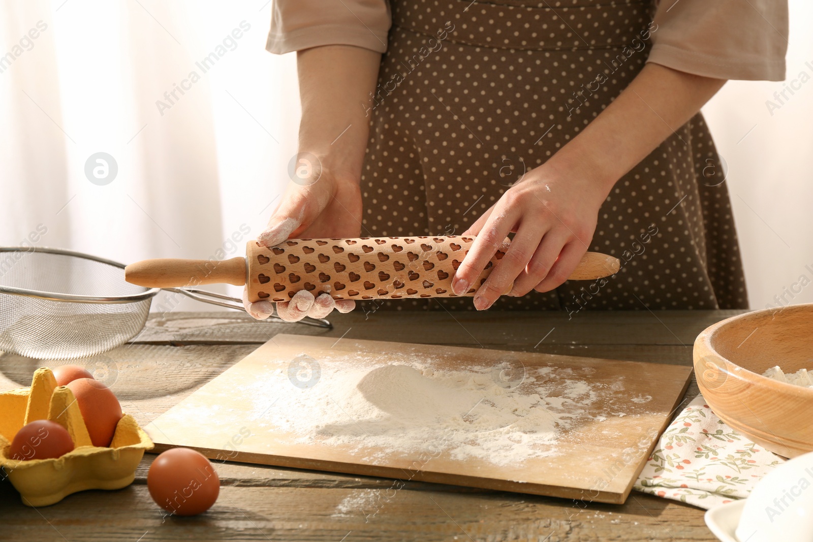 Photo of Woman with rolling pin at wooden table indoors, closeup