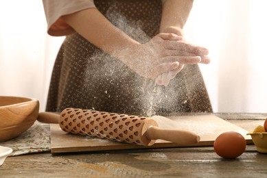 Photo of Woman with flour and rolling pin at wooden table indoors, closeup