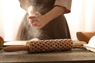 Photo of Woman with flour and rolling pin at wooden table indoors, closeup