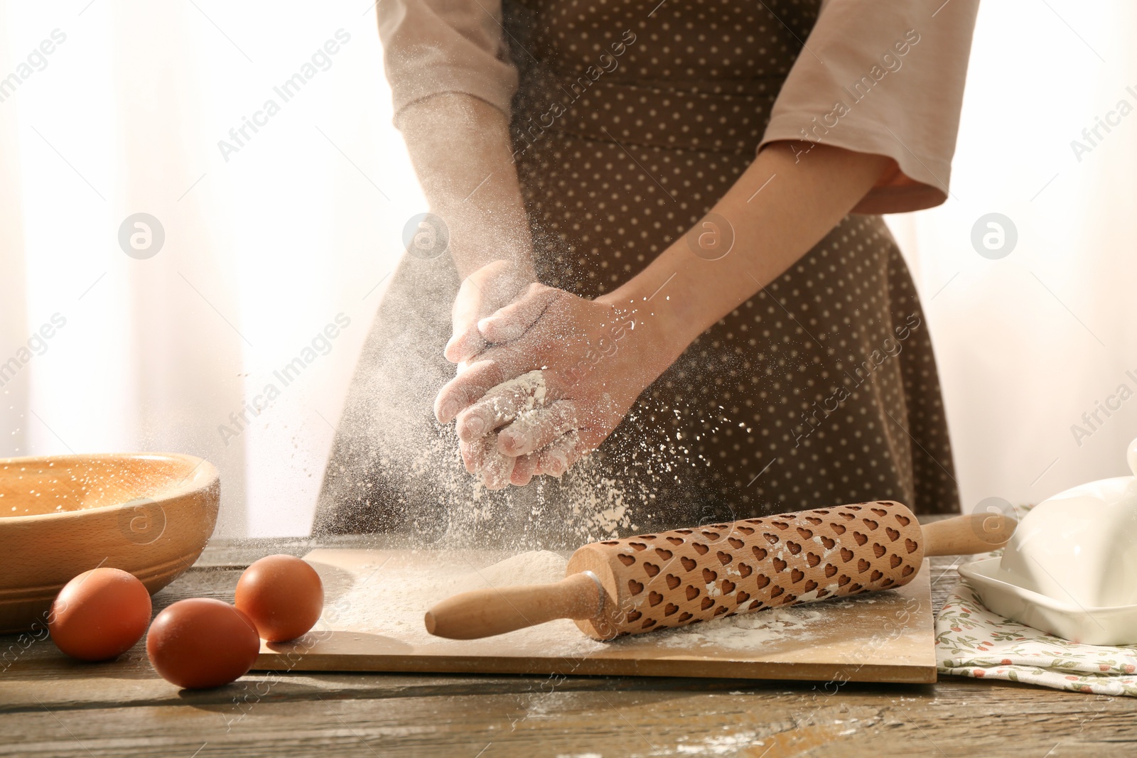 Photo of Woman with flour and rolling pin at wooden table indoors, closeup