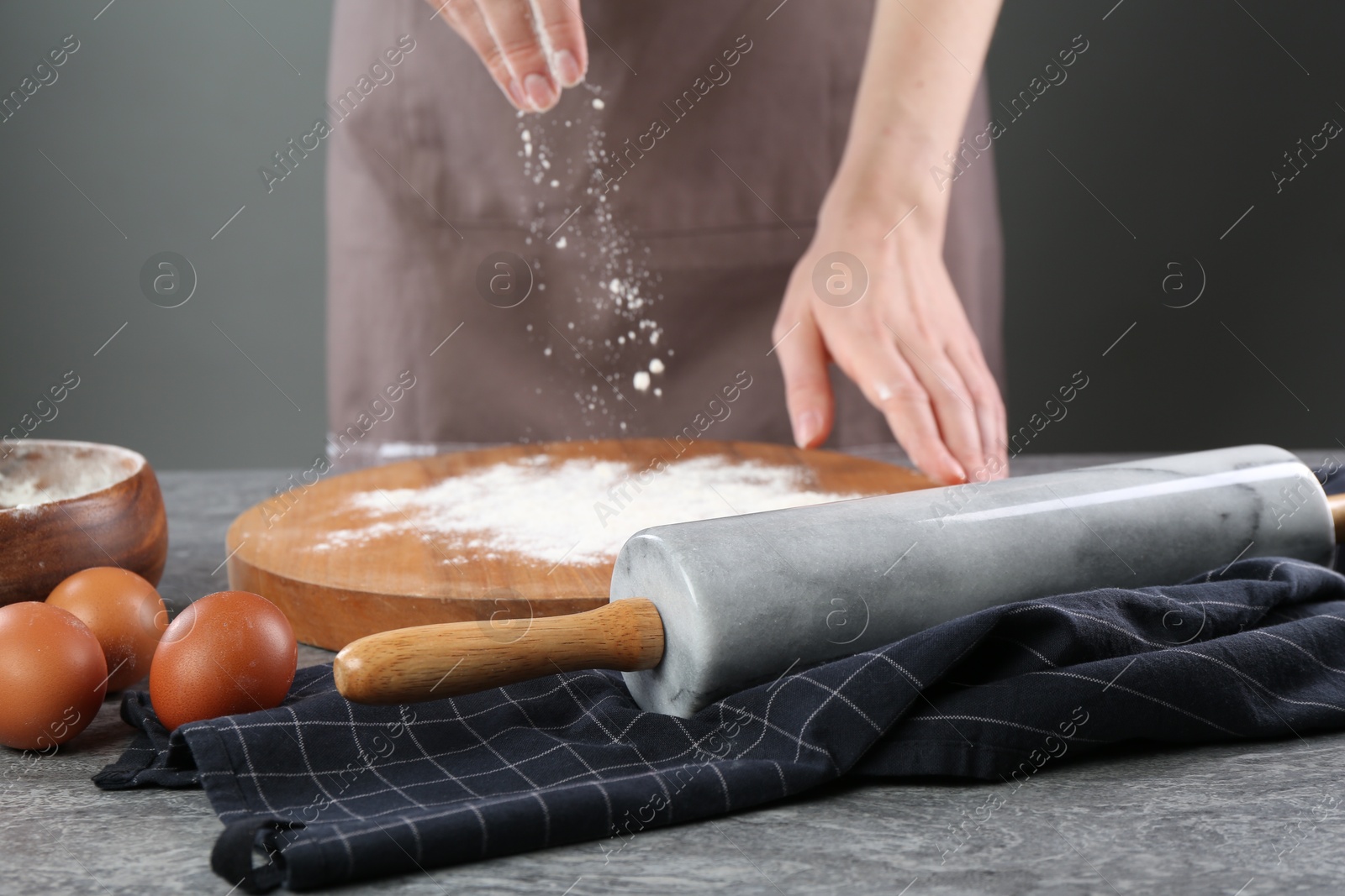 Photo of Woman with flour and rolling pin at grey table, closeup