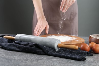 Photo of Woman with flour and rolling pin at grey table, closeup