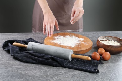 Photo of Woman with flour and rolling pin at grey table, closeup