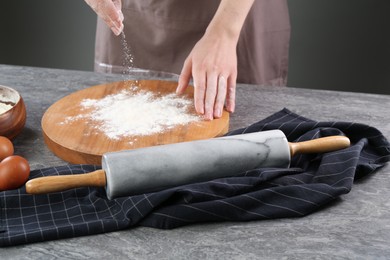 Photo of Woman with flour and rolling pin at grey table, closeup