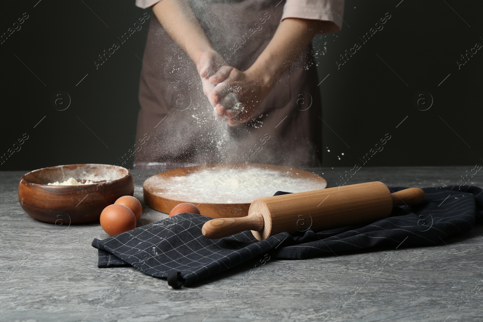 Photo of Woman with flour and rolling pin at grey table, closeup