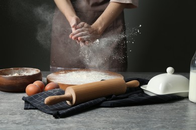 Photo of Woman with flour and rolling pin at grey table, closeup