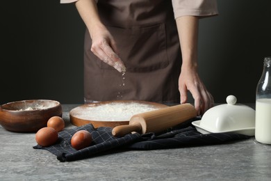 Photo of Woman with rolling pin and flour at grey table, closeup