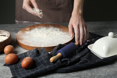 Photo of Woman with rolling pin and flour at grey table, closeup