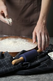 Photo of Woman with rolling pin and flour at grey table, closeup