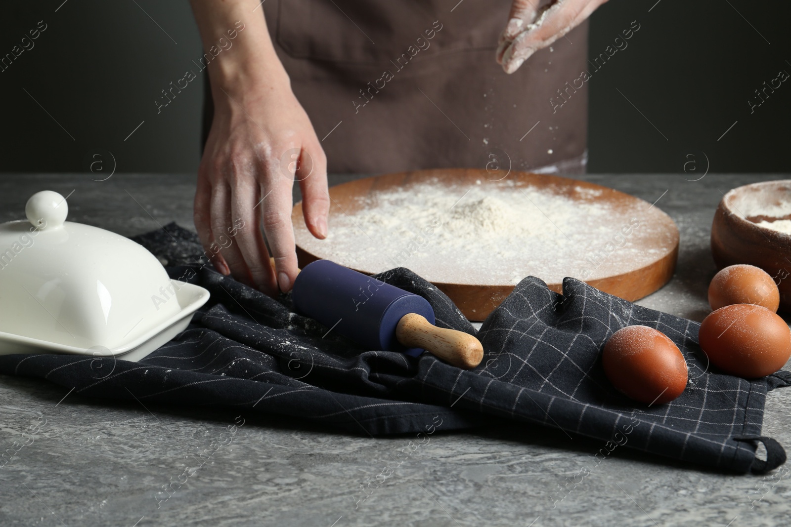 Photo of Woman with rolling pin and flour at grey table, closeup