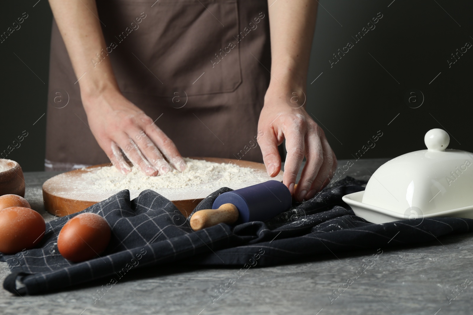 Photo of Woman with rolling pin and flour at grey table, closeup