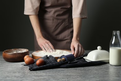 Photo of Woman with rolling pin and flour at grey table, closeup