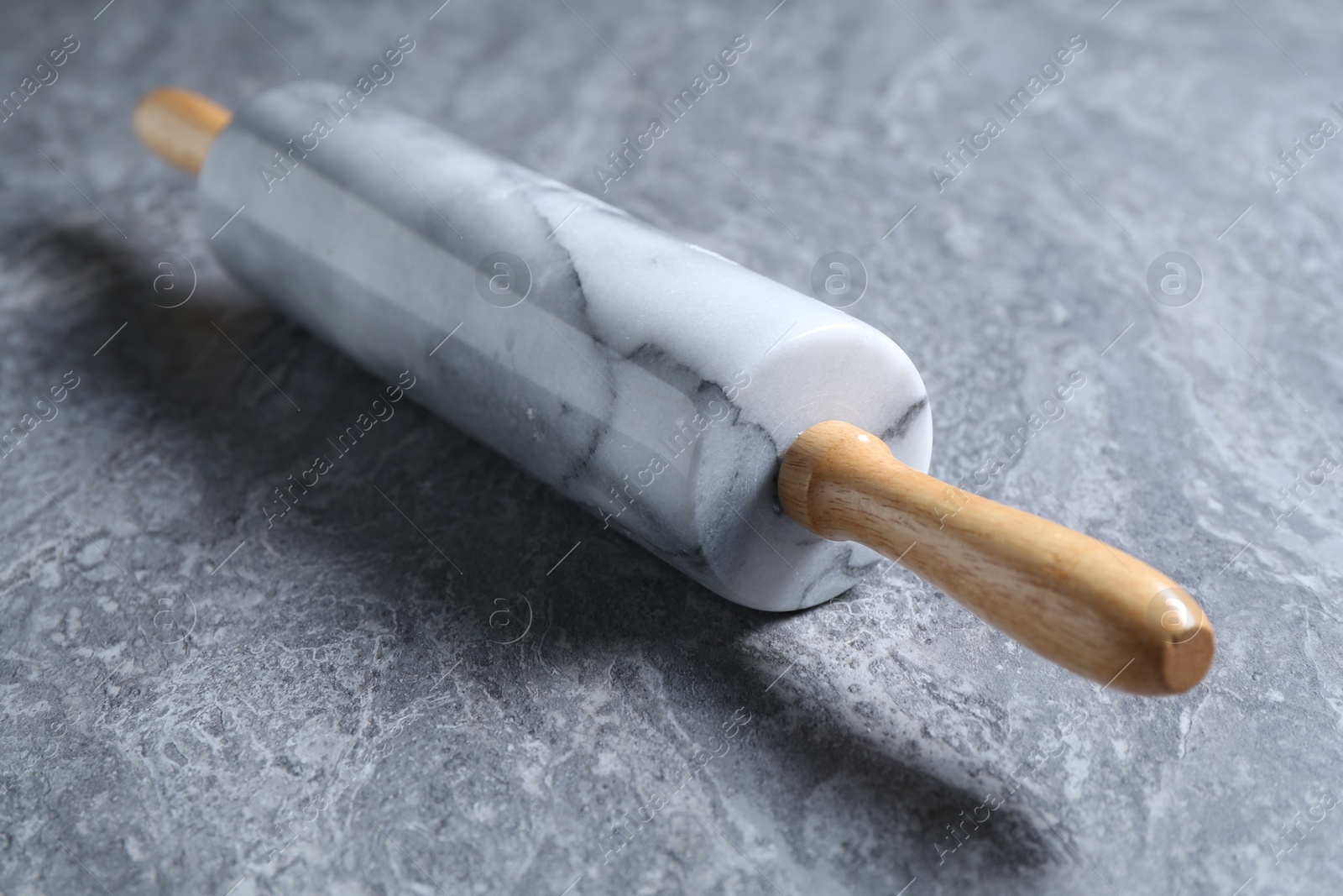 Photo of One rolling pin on grey textured table, closeup