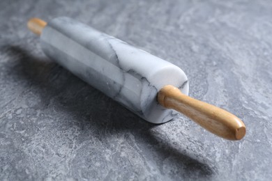 Photo of One rolling pin on grey textured table, closeup