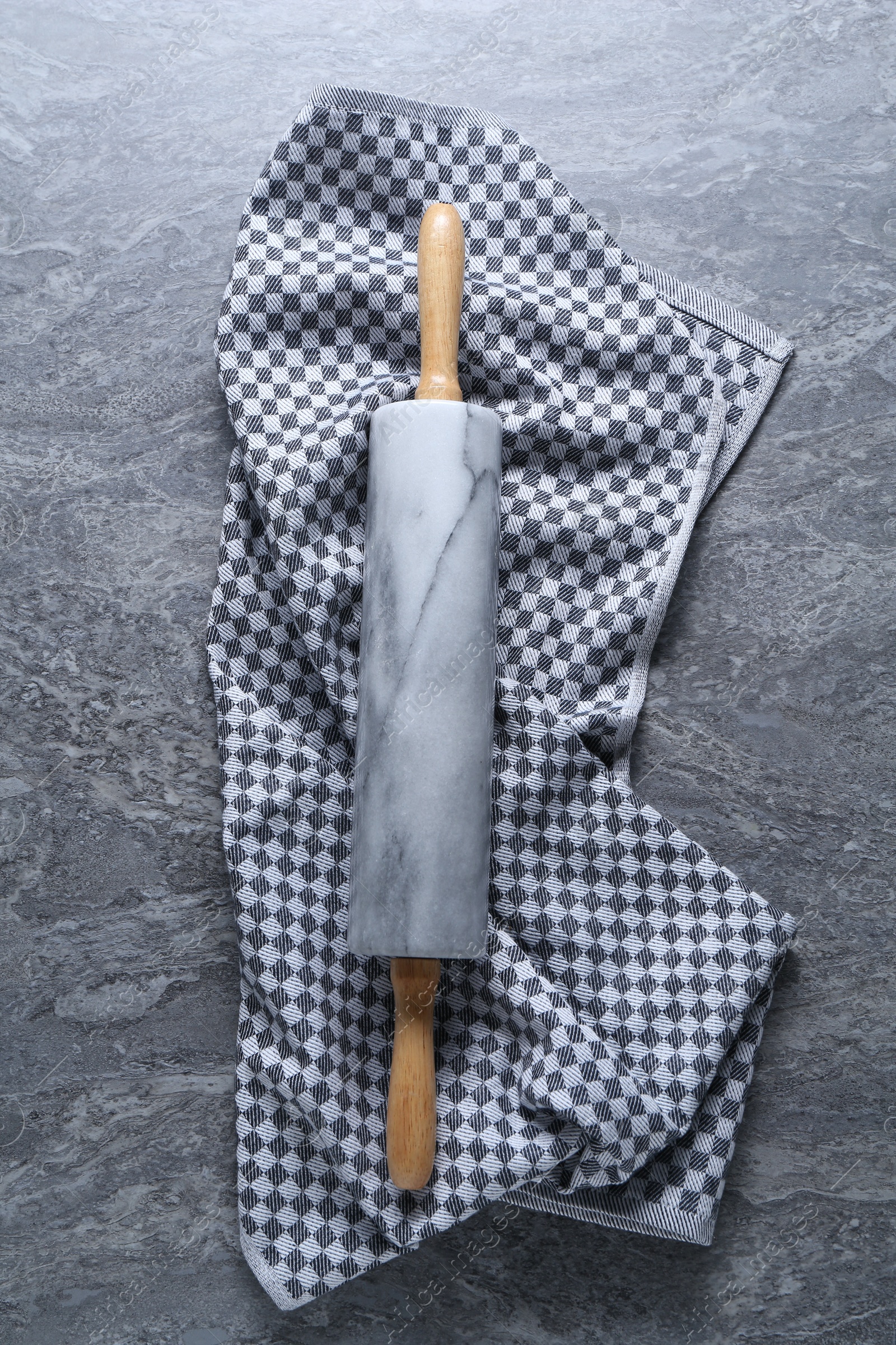 Photo of Rolling pin and kitchen towel on grey textured table, top view